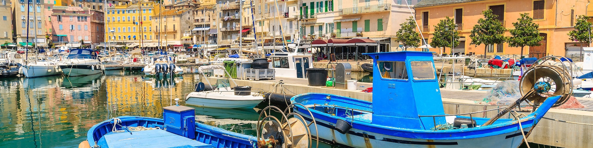 Un port avec des bateaux, des bùtiments et un ciel dégagé.