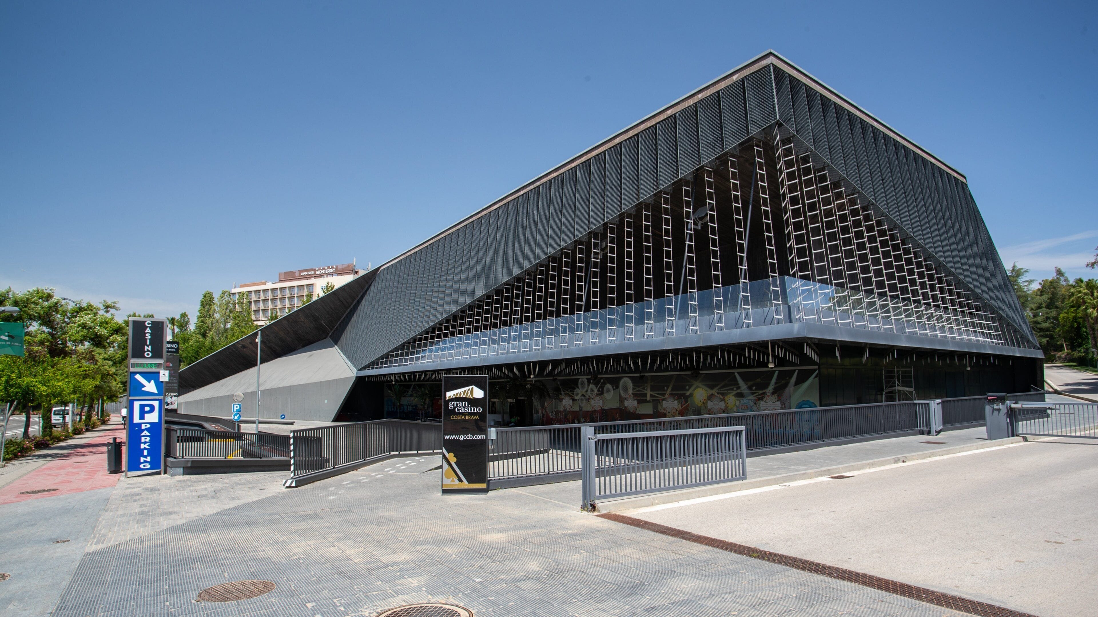 Un edificio moderno con un diseño triangular distintivo, un cartel de estacionamiento y una entrada con portón.