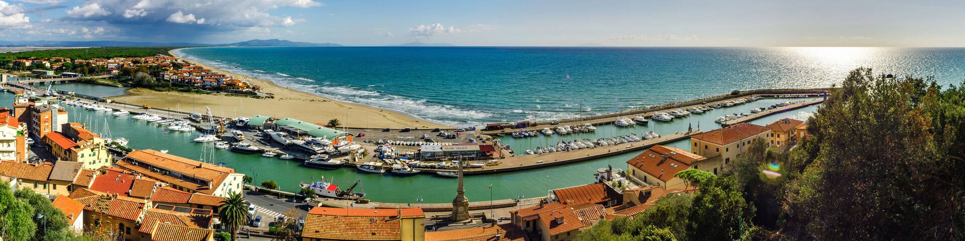 A coastal town with a marina, sandy beach, and a clear view of the sea.