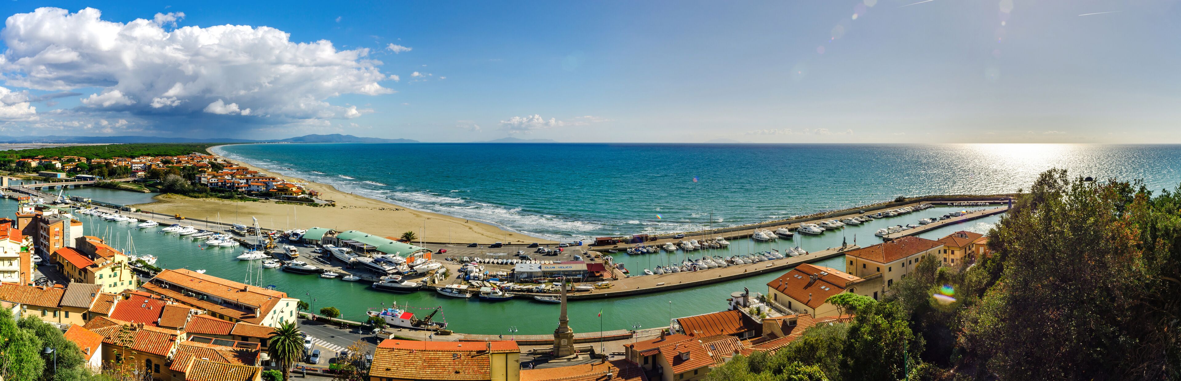 A coastal town with a marina, sandy beach, and a clear view of the sea.