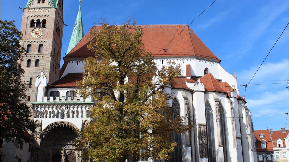 A historic church with a clock tower and a statue in front.
