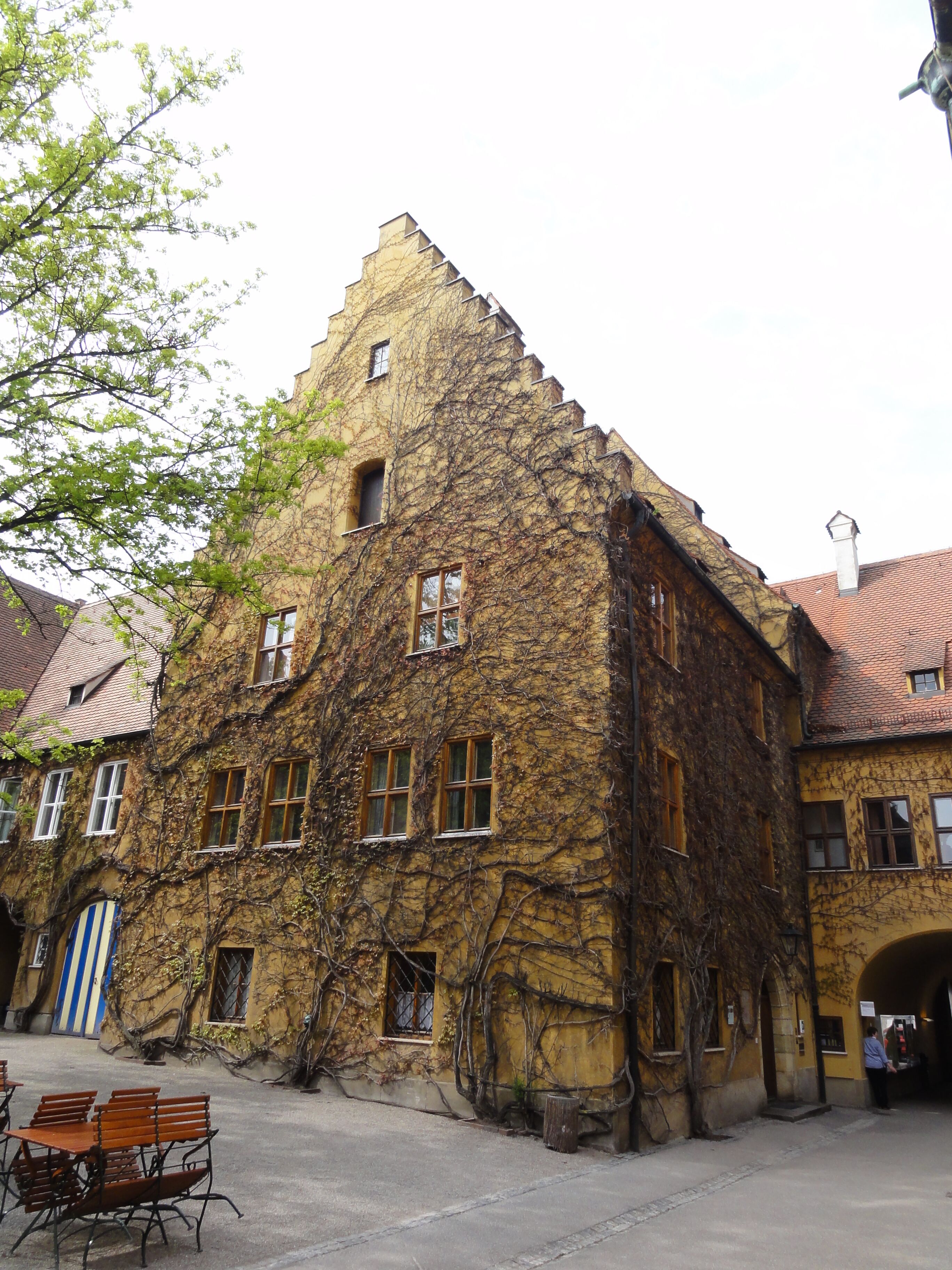 Een historisch pand met een muur begroeid met klimop en traditionele architectuur.
