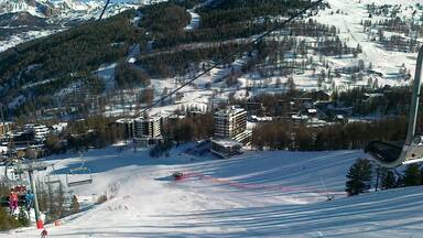 A ski slope with buildings and trees in the background.