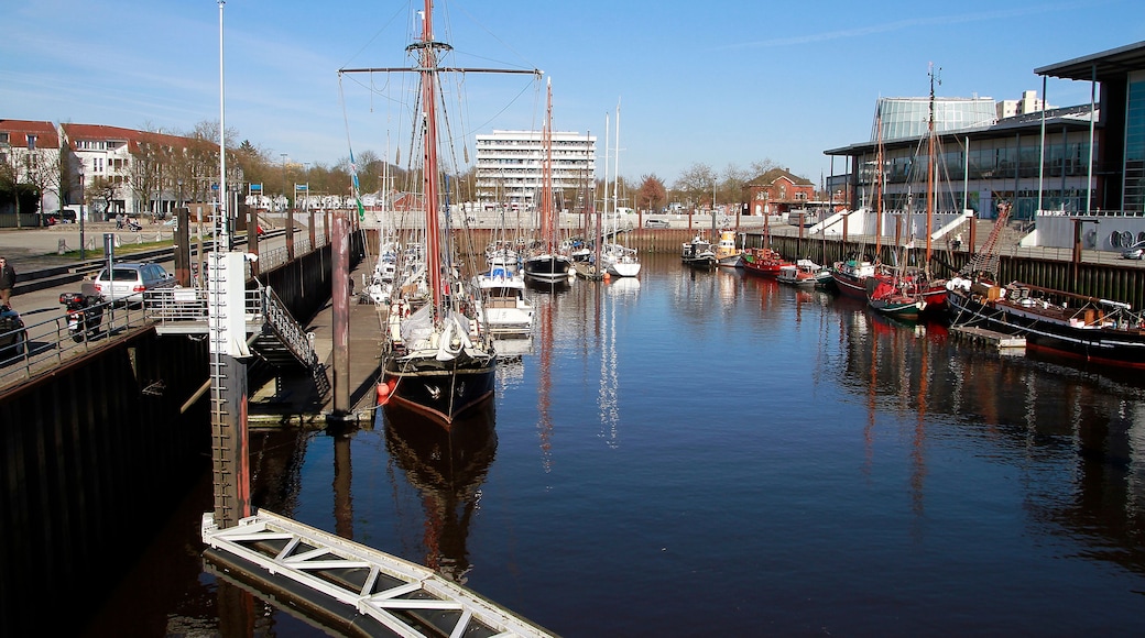 A marina with various boats docked, a bridge, and buildings in the background.