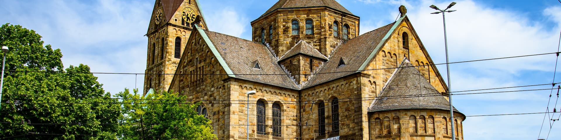 A historic church with a prominent clock tower and a smaller tower with a green roof.
