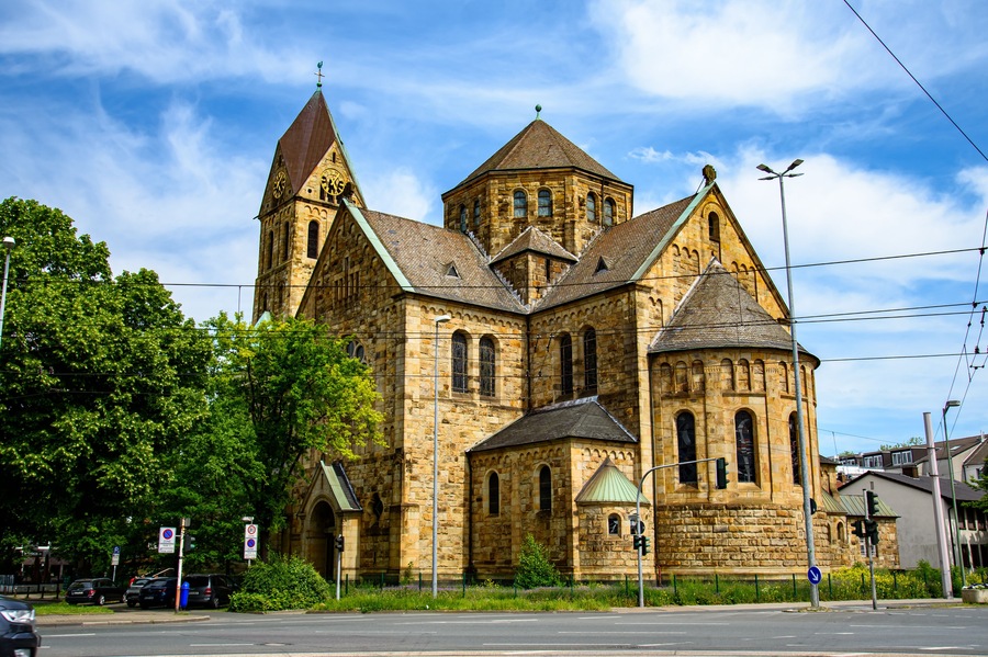 Eine historische Kirche mit einem markanten Glockenturm und einem kleineren Turm mit grüner Dachbedeckung.