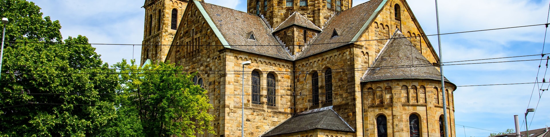 A historic church with a prominent clock tower and a smaller tower with a green roof.