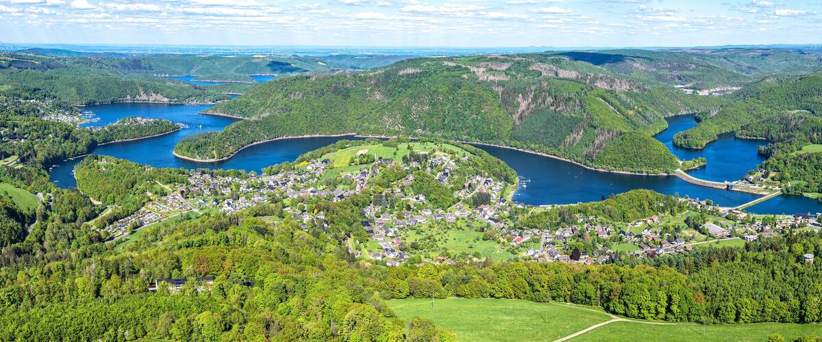 A river winding through a densely forested valley with a small town nestled along the riverbanks.