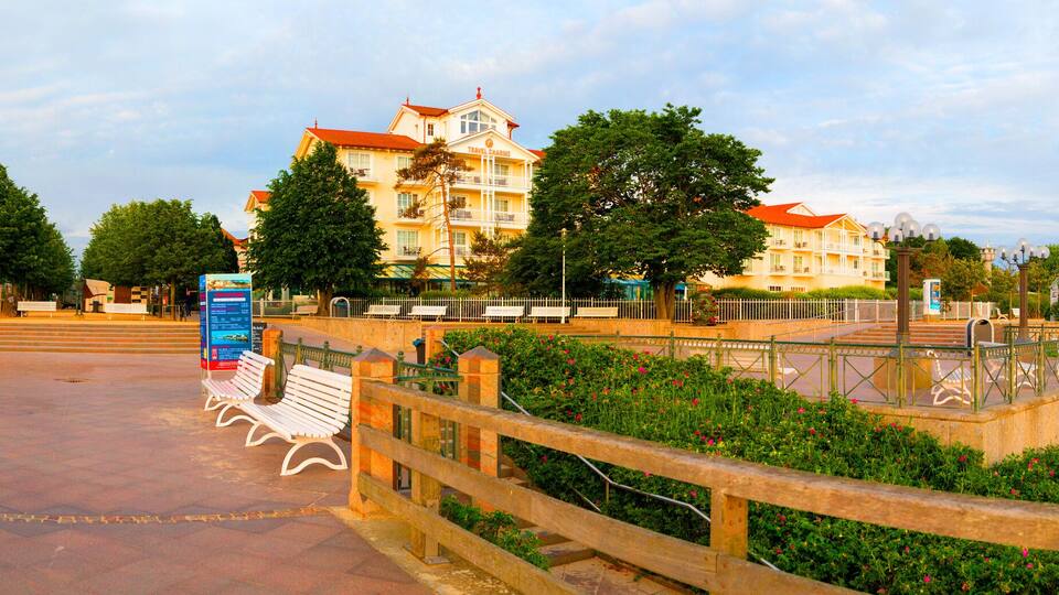 A promenade with benches, a bridge, and buildings with balconies.