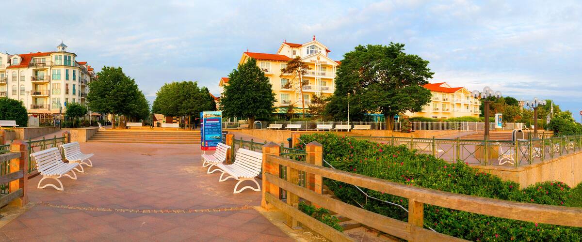 A promenade with benches, a bridge, and buildings with balconies.