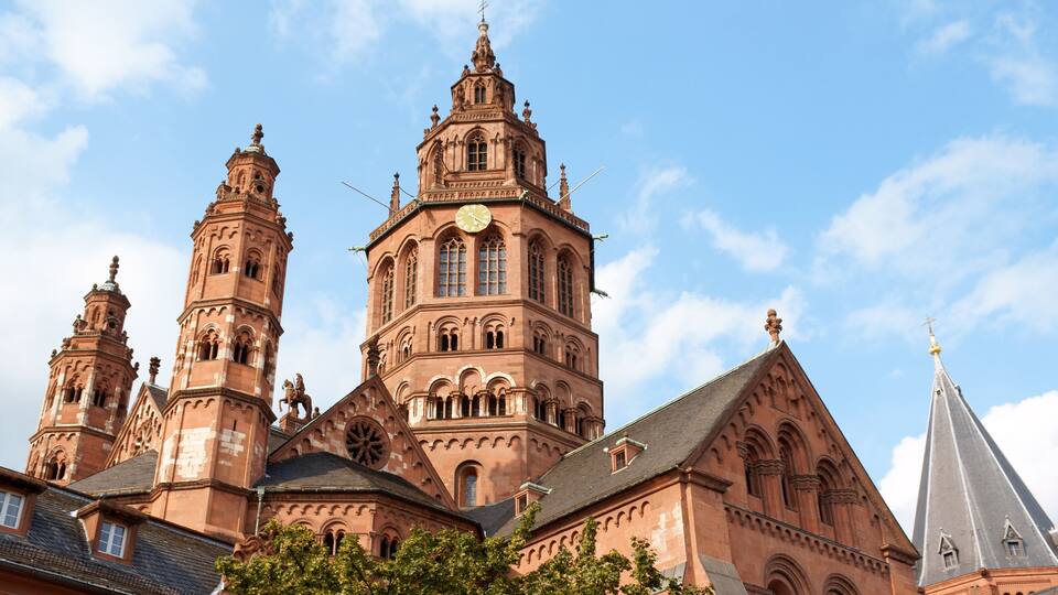 Een historisch kerkgebouw met een opvallende klokkentoren, gedetailleerde architectuur en een helderblauwe lucht.