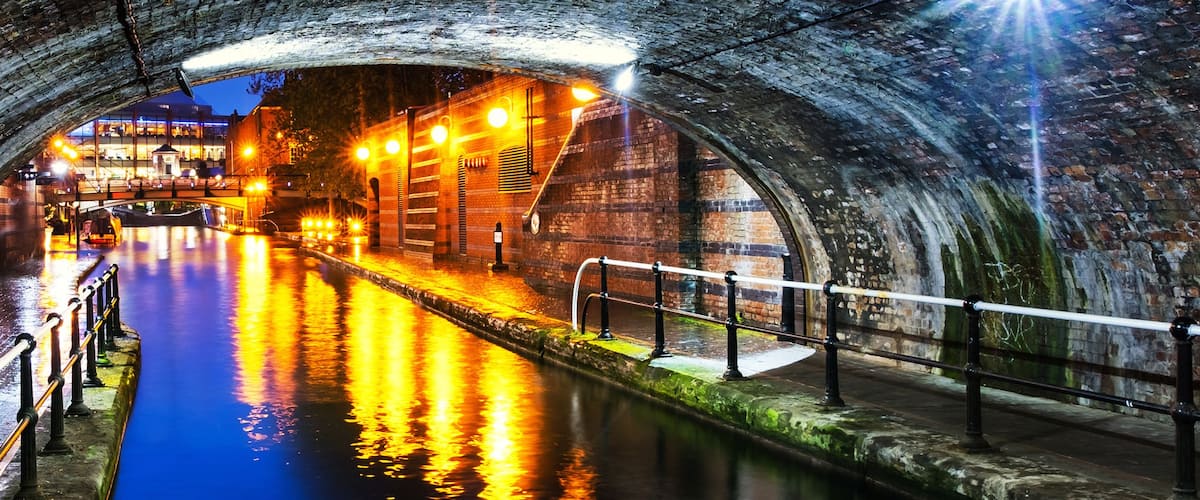 Tunnel in the city center during the rain, illuminated buildings at night, famous Birmingham canal in UK