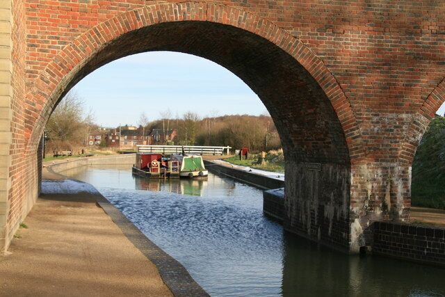 A brick bridge over a canal with a boat.