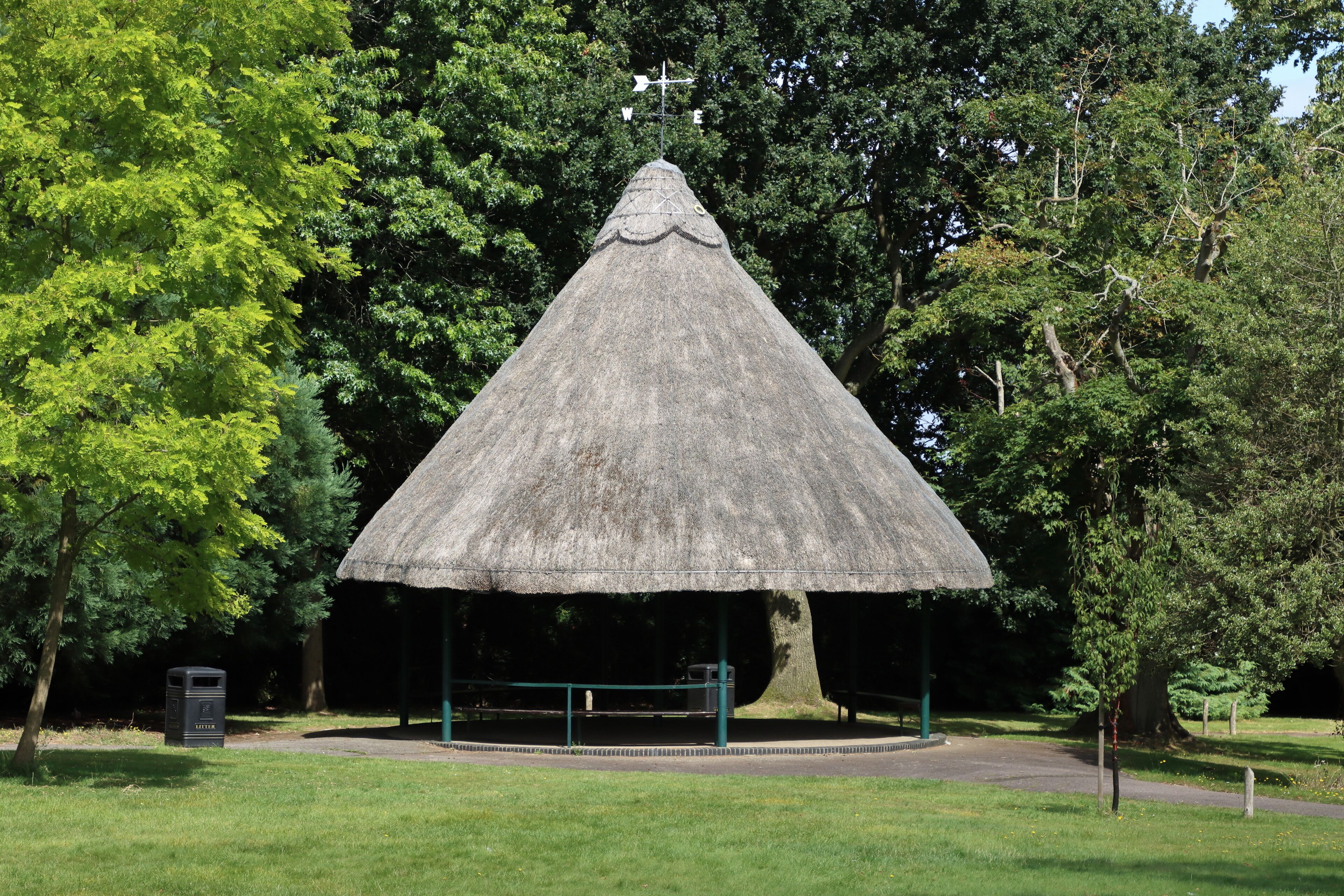A thatched-roof pavilion surrounded by trees.