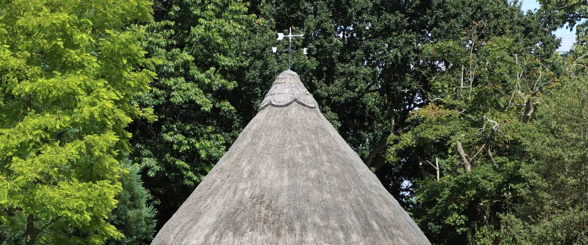 A thatched-roof pavilion surrounded by trees.
