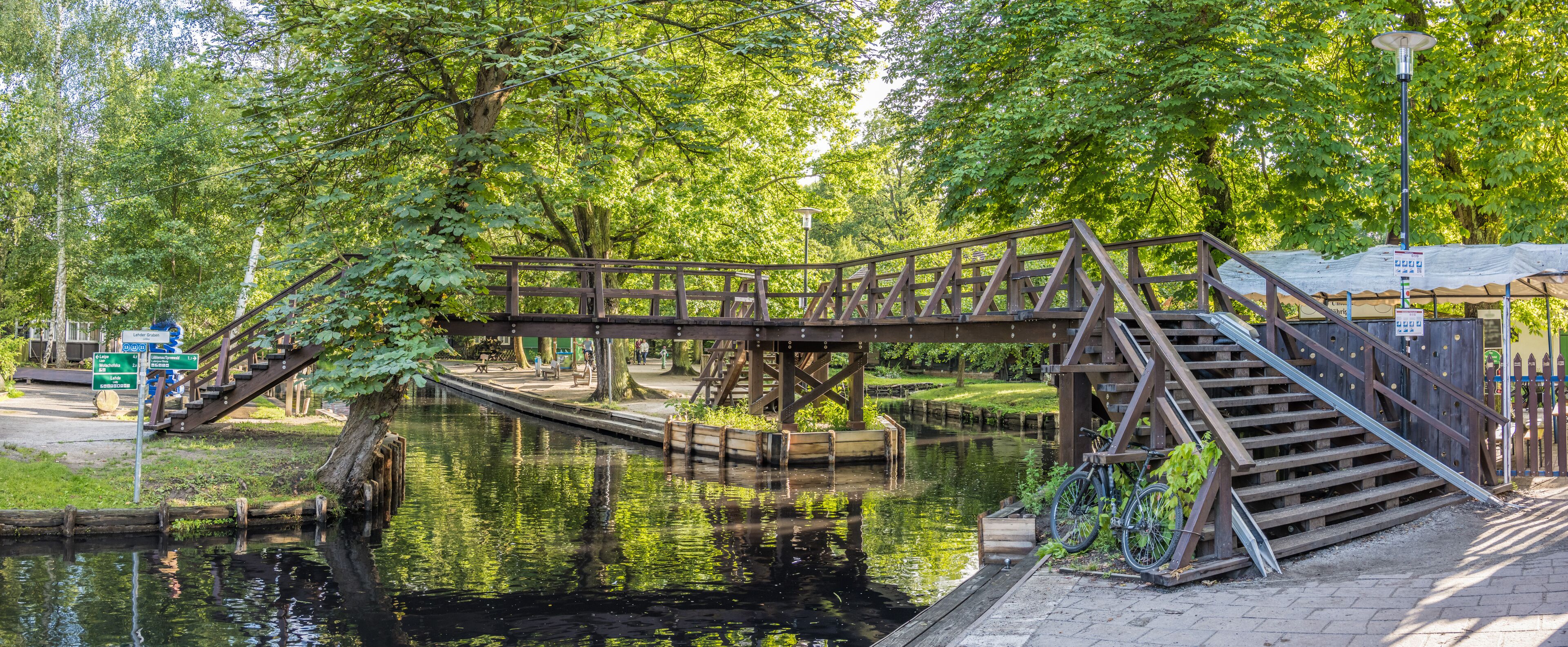 A wooden bridge over a canal with a bicycle parked nearby.