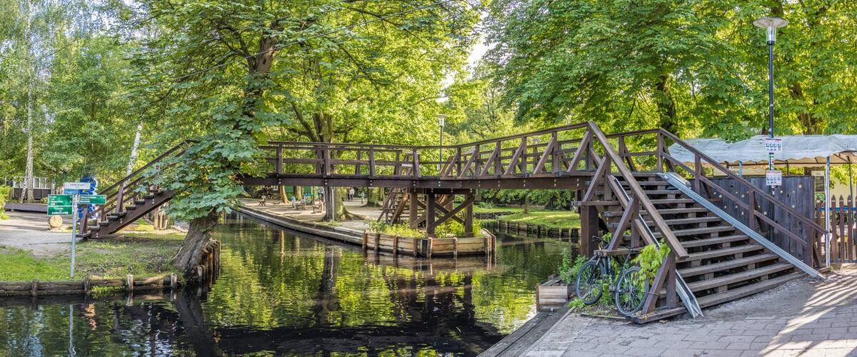 A wooden bridge over a canal with a bicycle parked nearby.