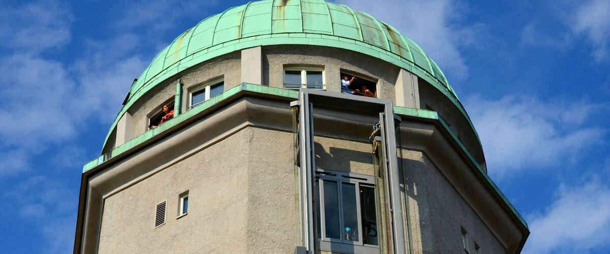 Una torre alta con una cúpula verde y una escalera de metal que conduce a una ventana.