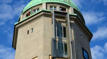 Un'alta torre con una cupola verde e una scala in metallo che conduce a una finestra.