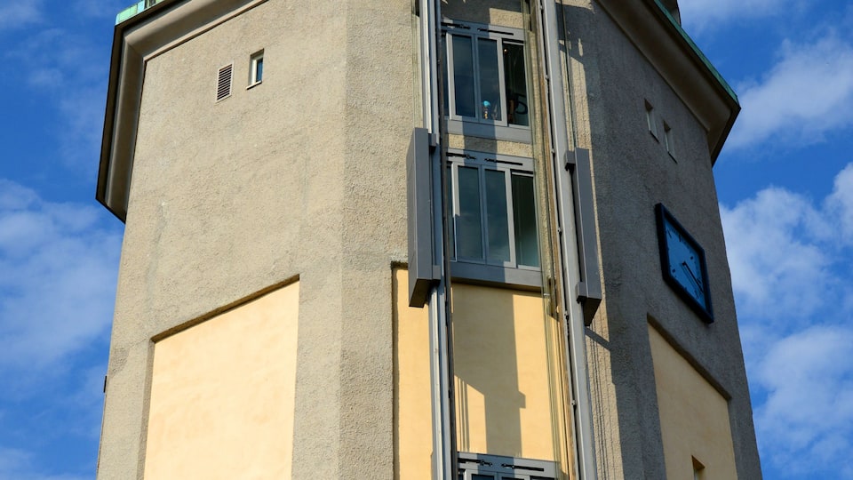 A tall tower with a green dome roof and a metal staircase leading to a window.