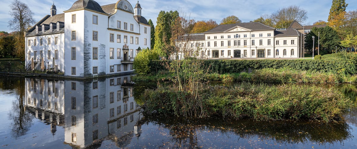 Ein großes, weißes Gebäude mit vielen Fenstern und Spiegelung im Wasser.