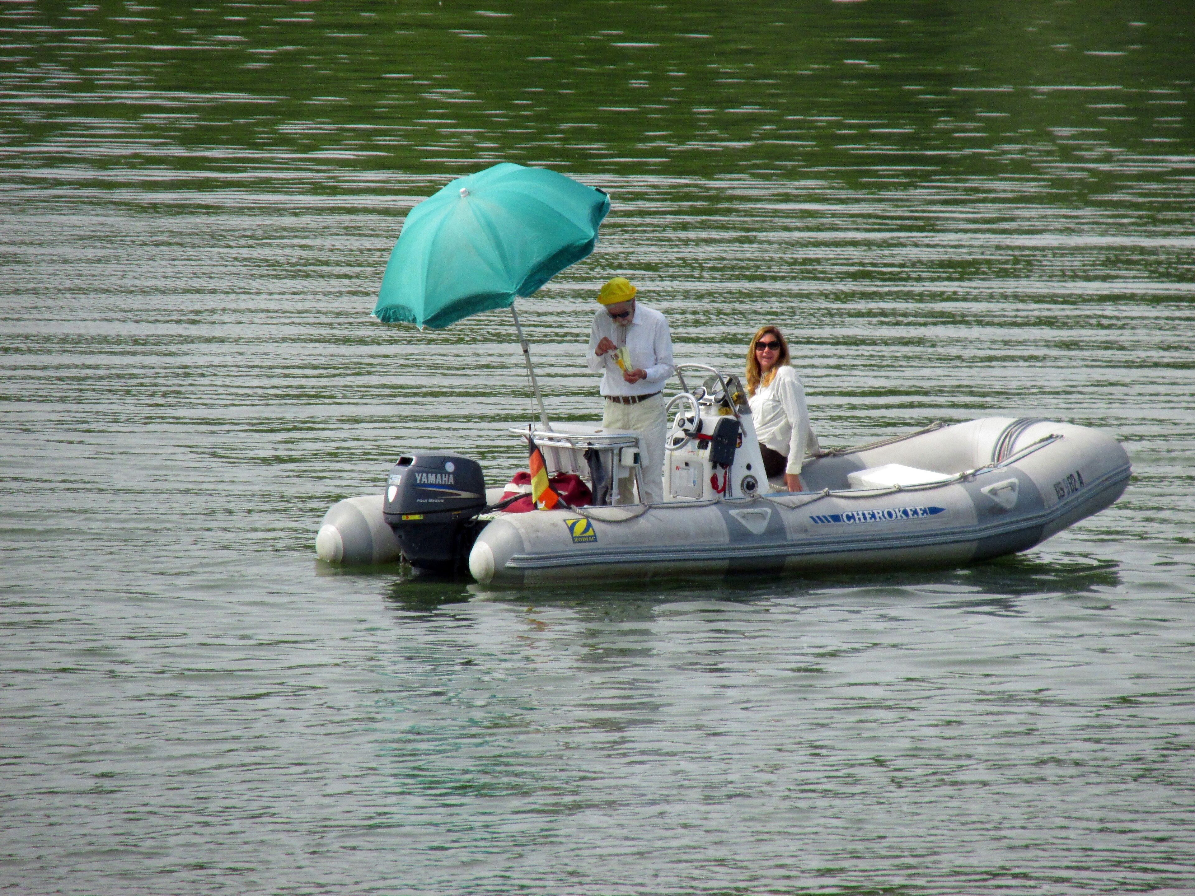 A small inflatable boat on calm water with a blue canopy and a Yamaha outboard motor.