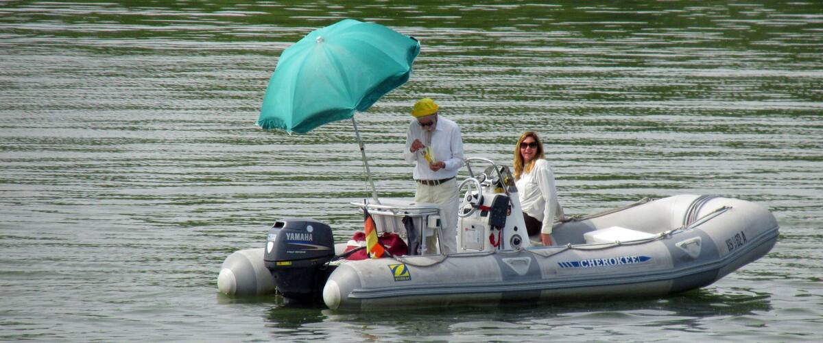 A small inflatable boat on calm water with a blue canopy and a Yamaha outboard motor.