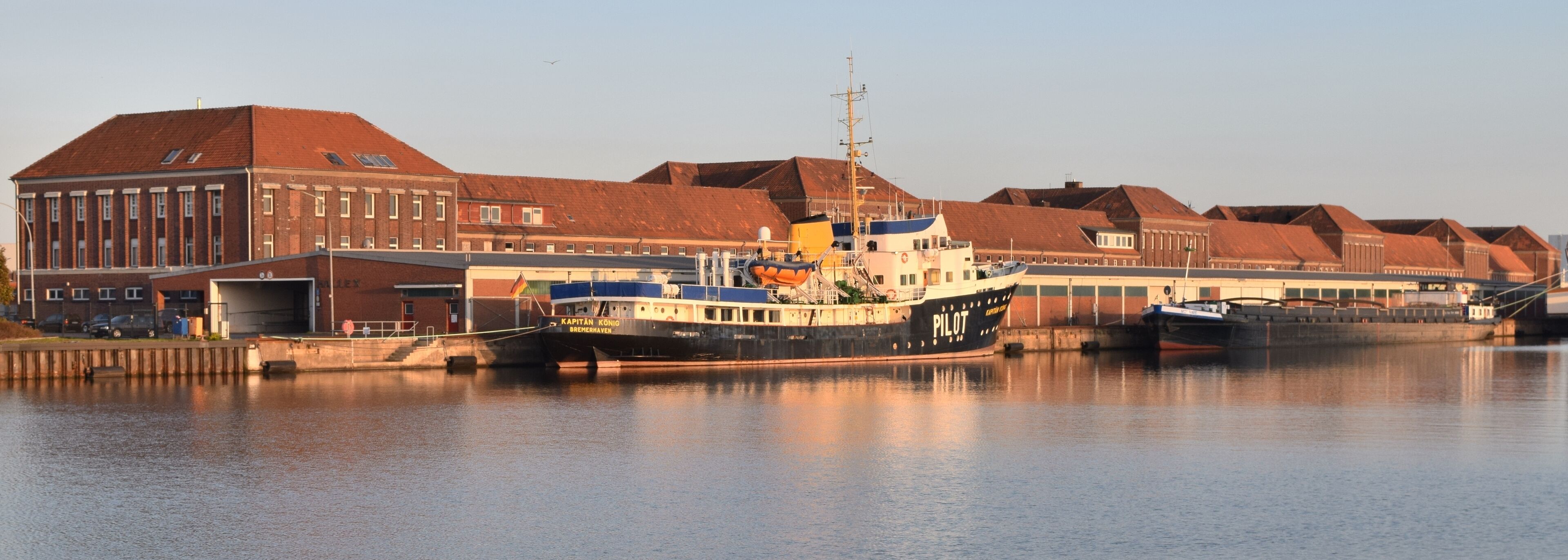 A harbor with a large ship named "Kapitan Konio" docked.