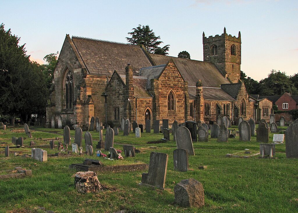 A historic church with a tall tower and a graveyard in front.