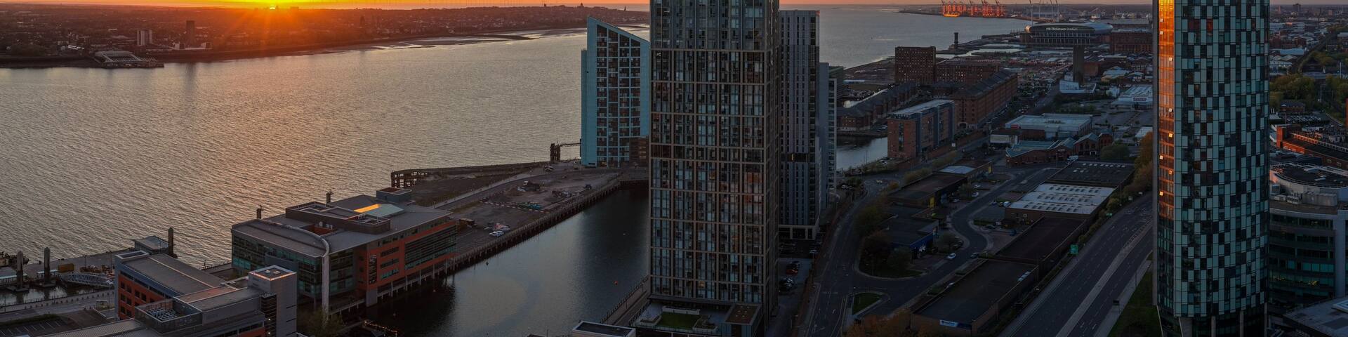 A sunset over a city with modern buildings and a river.
