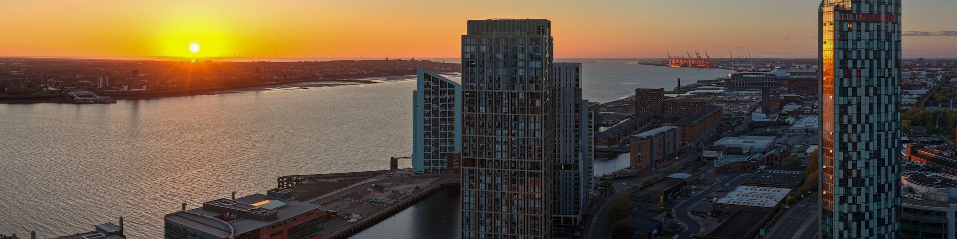 Un atardecer sobre una ciudad con edificios modernos y un río.