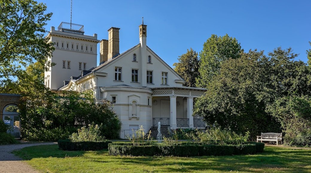 A large, historic building with a prominent tower and multiple chimneys.