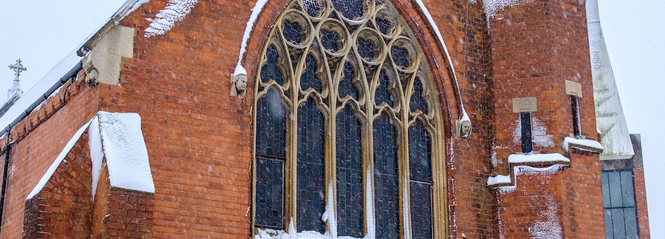 Eine schneebedeckte Kirche mit einem markanten Bogenfenster und einem Glockenturm.