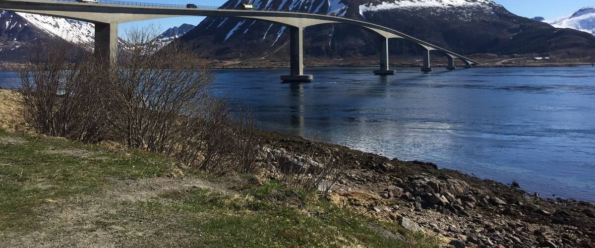 A bridge over a river with mountains in the background.