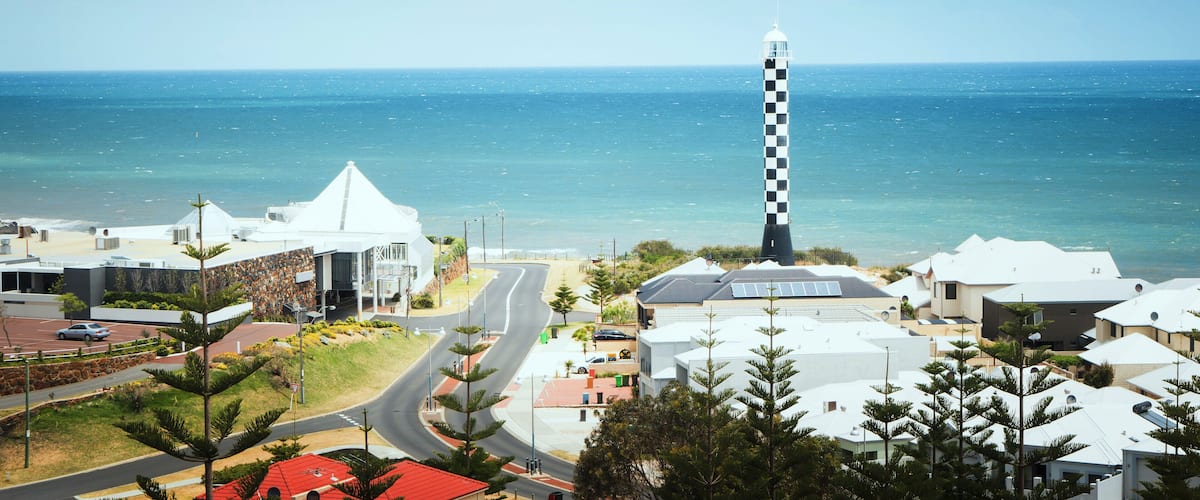 A coastal town with a prominent lighthouse, a beach, and residential buildings.