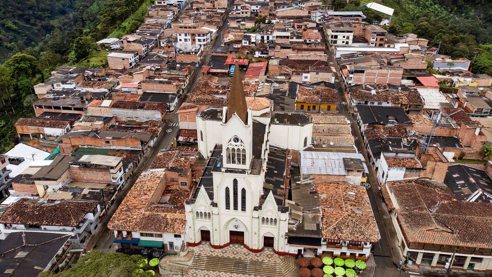 An aerial view of a historic town with a prominent church featuring a tall bell tower and a tiled roof.