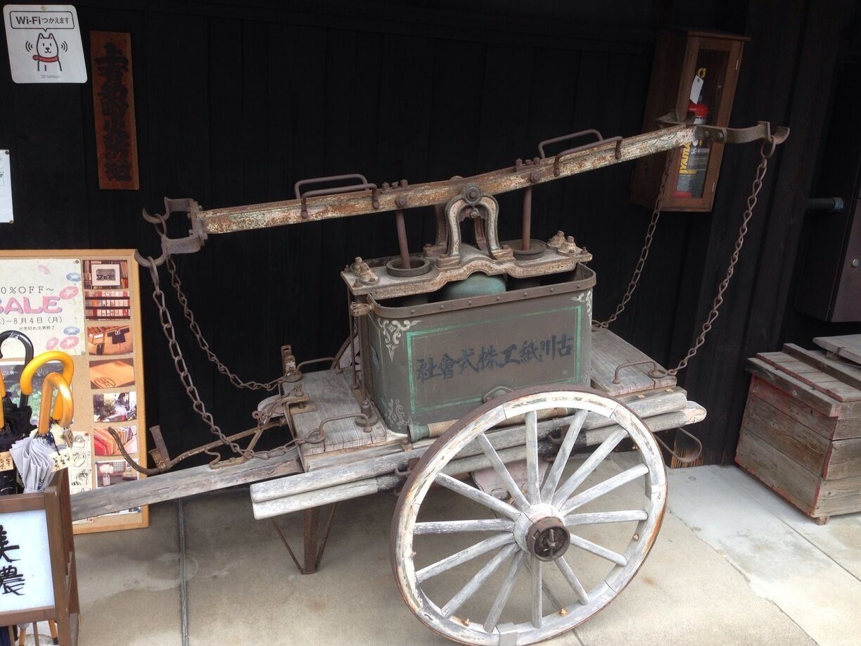 An old-fashioned cart with a wooden frame and metal fittings, chained to a wall.