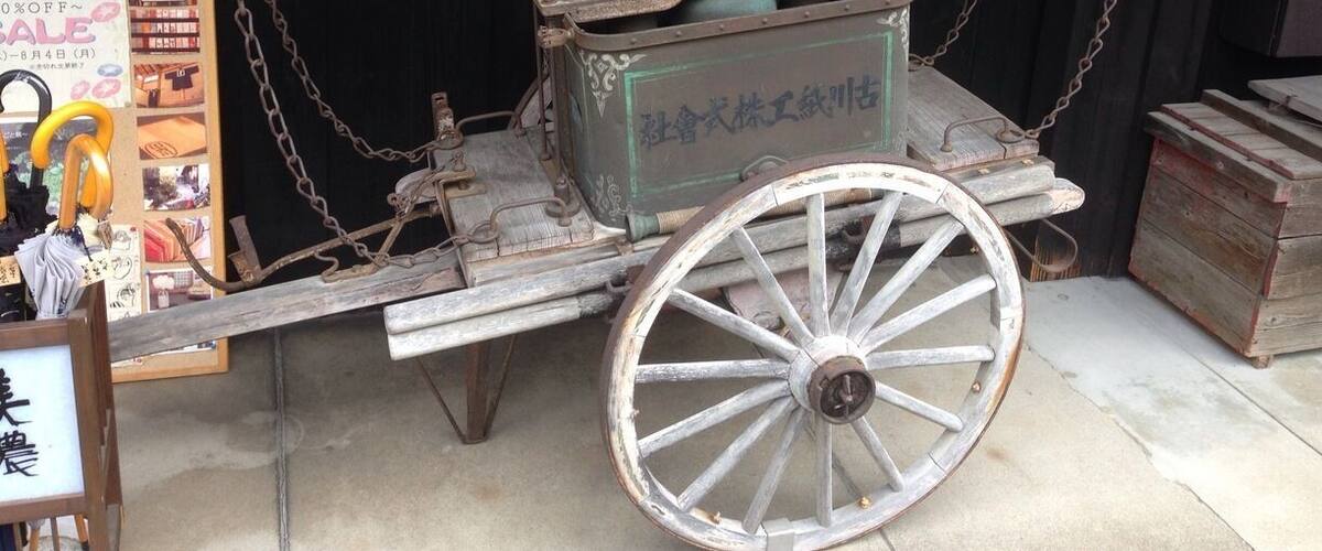 An old-fashioned cart with a wooden frame and metal fittings, chained to a wall.