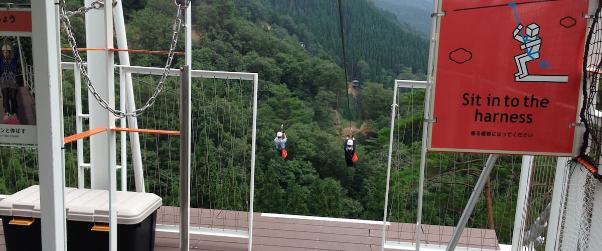A zip-lining platform with a sign instructing to sit in the harness.