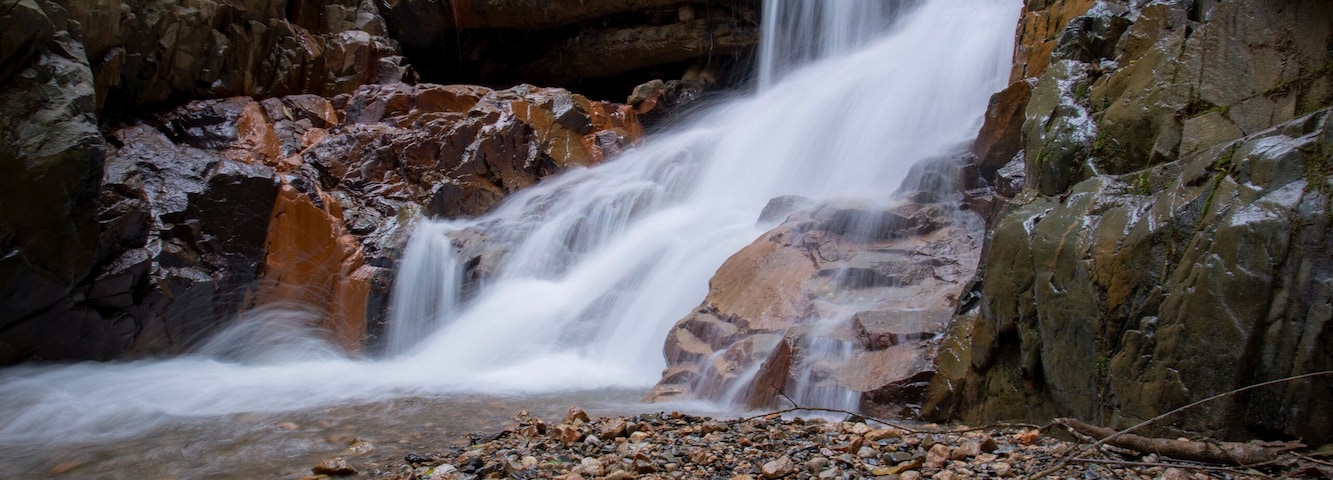 Une cascade d’eau qui dévale des rochers dans une zone boisée.