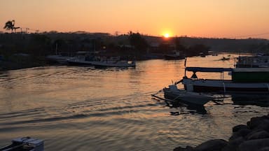 A sunset over a calm river with boats docked along the shore.