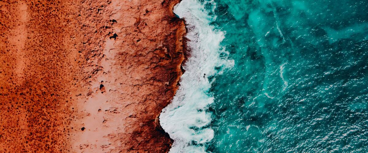 A coastal landscape with a sandy beach and turquoise ocean waves.