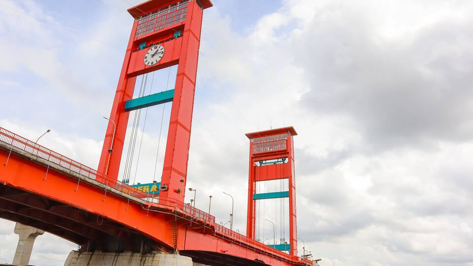 A red bridge with a clock tower and a smaller tower.