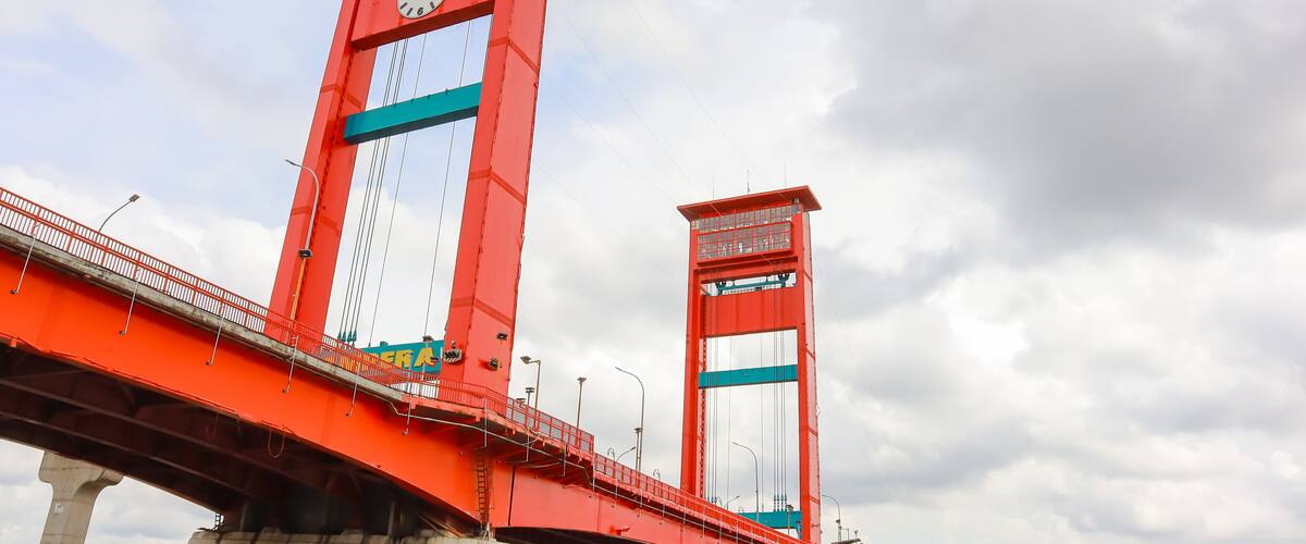 A red bridge with a clock tower and a smaller tower.