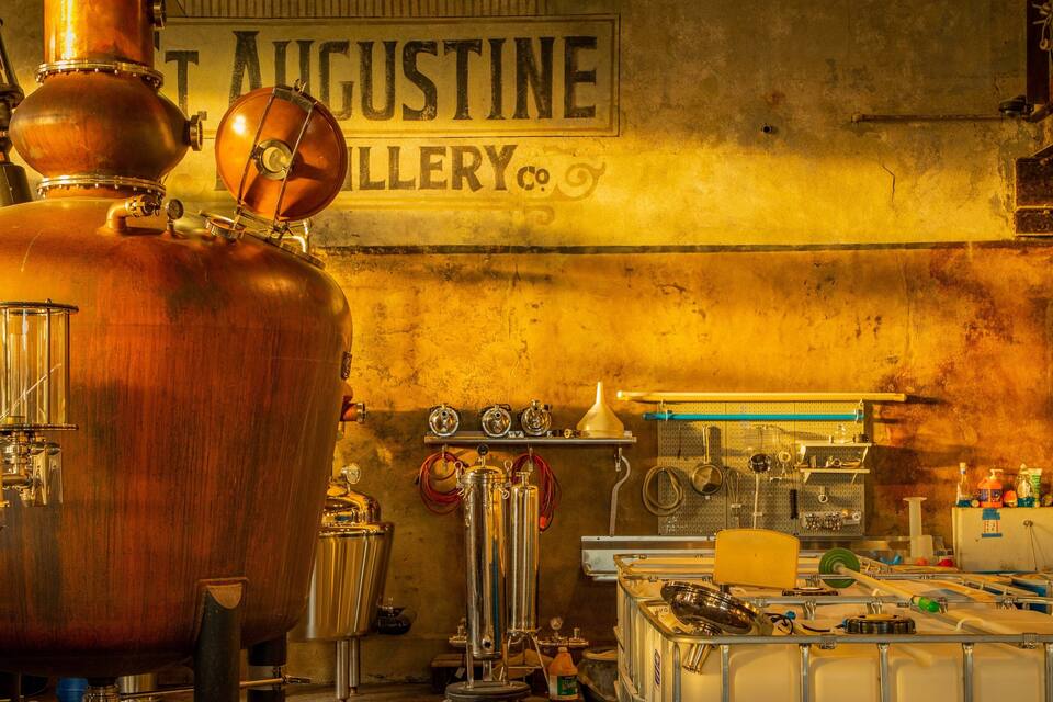 A distillery with large copper stills and a sign reading "T. Augustine Gallery Co."