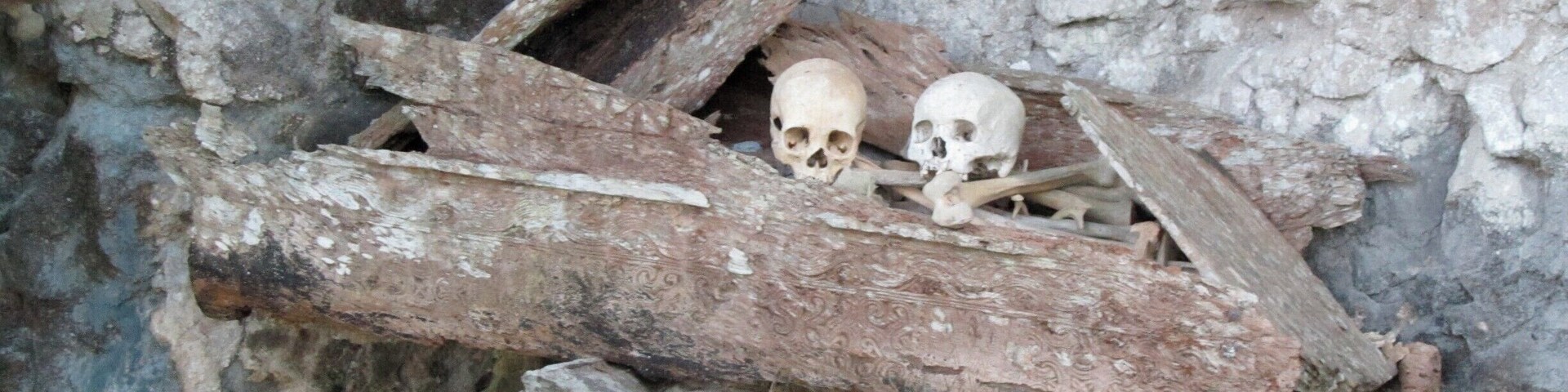 A wooden structure with two skulls inside, set against a rocky background.