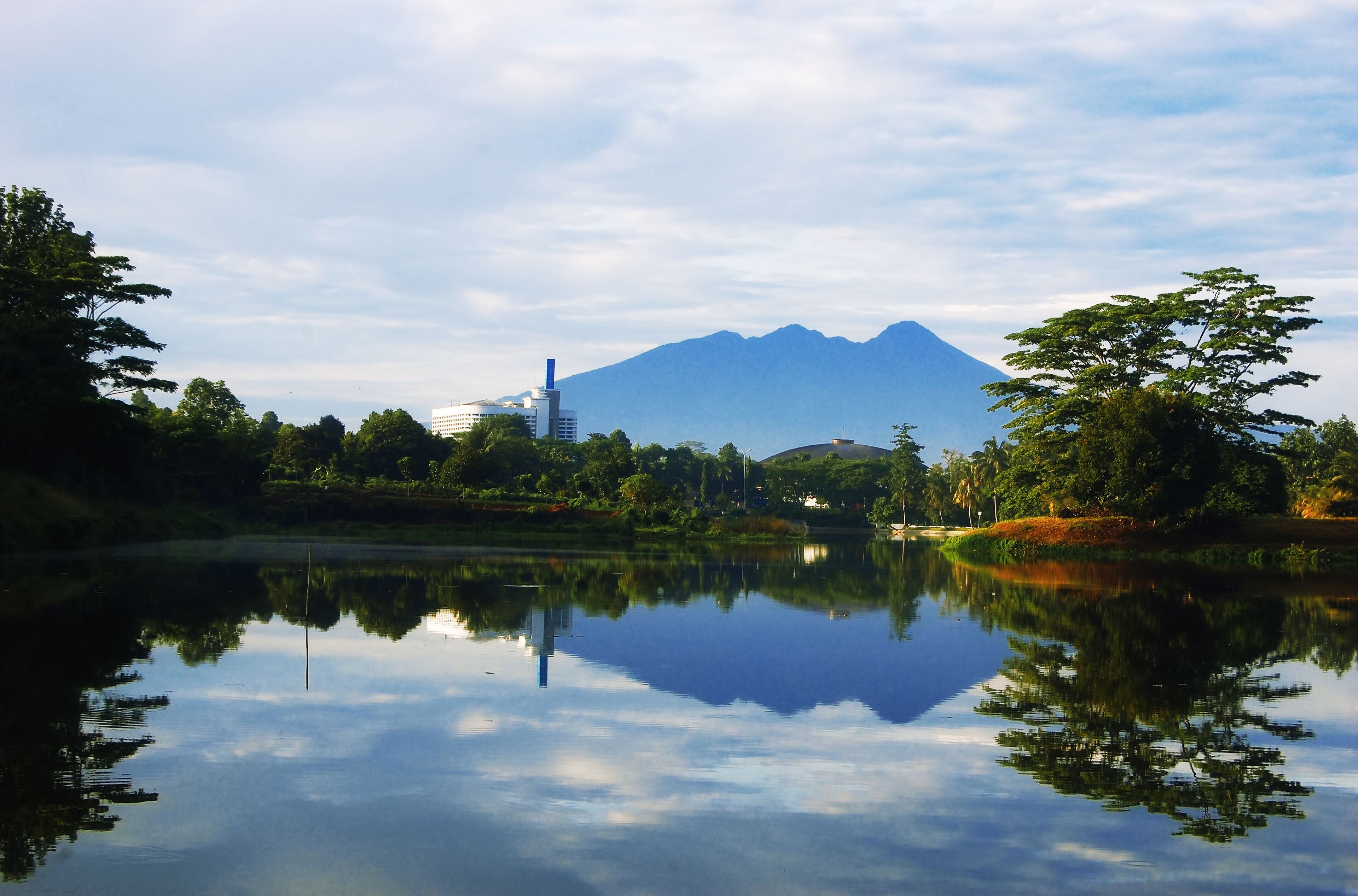 A calm lake with a mountain in the background and buildings near the water's edge.