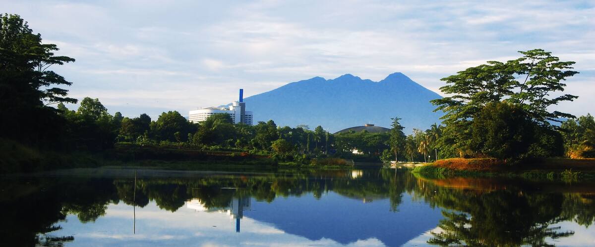 A calm lake with a mountain in the background and buildings near the water's edge.