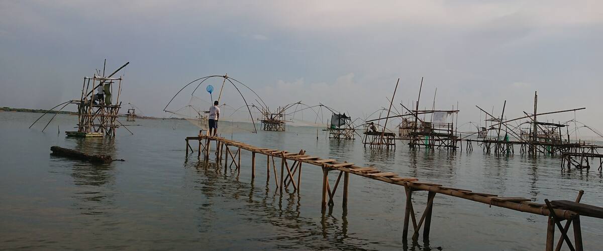 A calm body of water with wooden fishing platforms and nets.