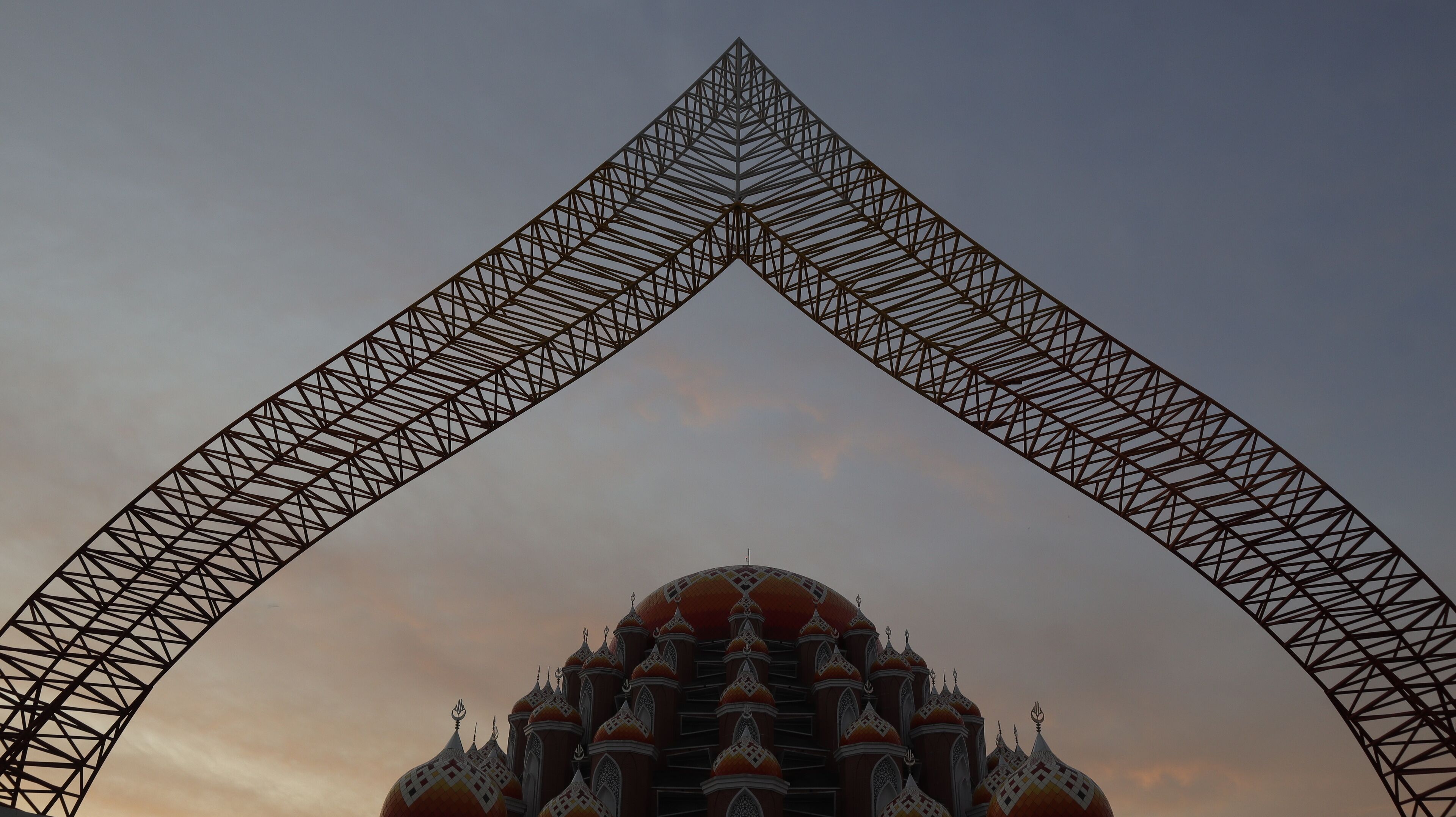 A large arch structure framing a domed building with intricate patterns.